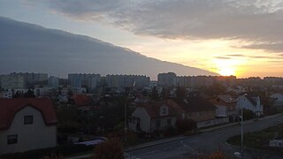 "Das ist die Aussicht von meinem Fenster. Unser Reihenhaus ist auf einem Hügel und wir leben in eine Wohnung auf die dritte Etage, damit wir eine sehr schöne Aussicht haben. Ich lebe in Stodůlky, eine Stadtviertel von Prag. Prag hat 1.3 Mio. Einwohner. Ich mag meine Stadtteil, weil es in die Zentrum liegt nicht; es ist ruhig und hat viele große Grünanlage. Aber die Reise ins Zentrum ist kurz Dank an die Metro."
