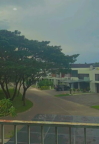 Hallo! Das ist der Blick aus meinem Fenster. Von meinem Fenster aus kann ich andere Häuser und die Straße sehen. Palembang ist eine ziemlich große Stadt mit über 1.843 Millionen Einwohnern. Ich lebe jedoch in einem Wohngebiet in der Nähe des Stadtrandes. Mein Haus ist weit von meiner Schule entfernt, es dauert 30 Minuten, um dorthin zu gelangen.