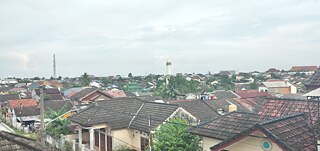 Hi! Das ist meine Fensteransicht. Ich lebe am Palembang stadtrand und hier leben viele personen. Palembang is ein groß stadt mit 1.843 Millionen Einwohnern. Meine Scule ist 9,5 km von hier, deshalb ich brauche 30 minuten für reise zur die Schule. In das Foto, sehen Sie viele Häuser und zweien Moscheen. Palembang ist eine dichte Stadt, aber die meisten Einwohner haben ein glückliches Leben. Also, haben wir ein neues Stadtbahn, denn ASIAN Games 2018 Veranstaltung.