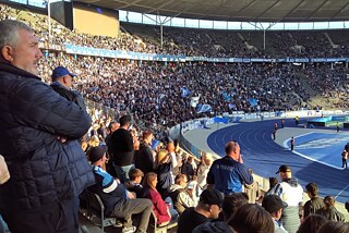 Blick ins und aus dem Publikum auf ein Fußballstadion