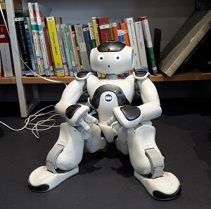 Roboter Gaia sitzt vor Bücherregal