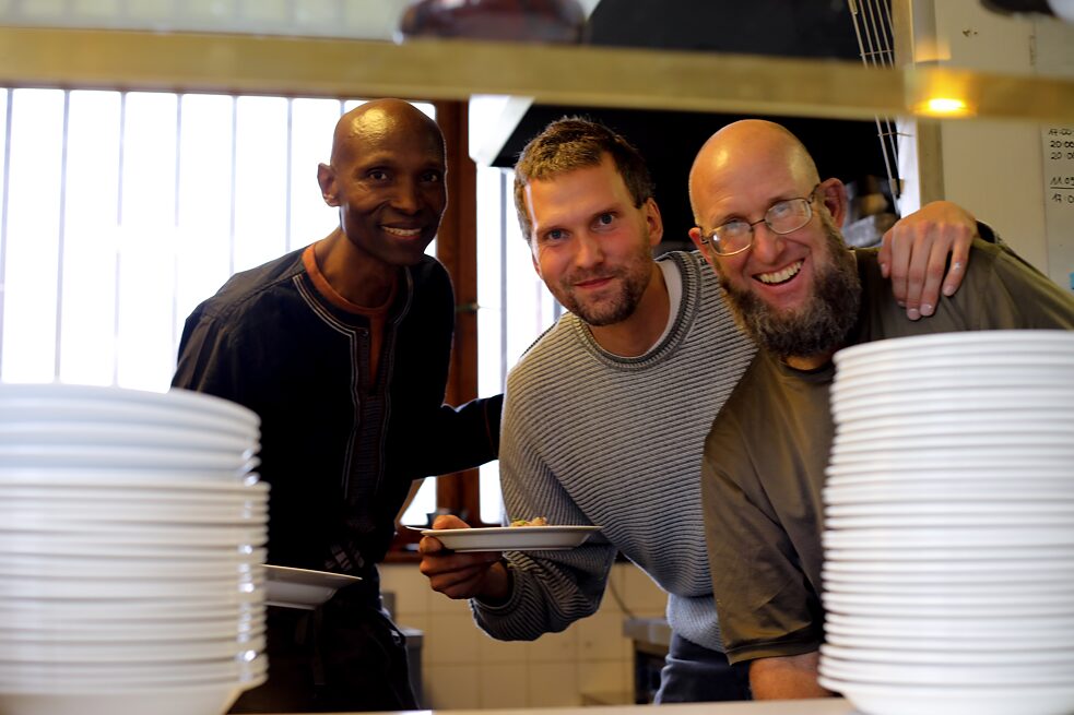 Three people in the kitchen presenting a plate