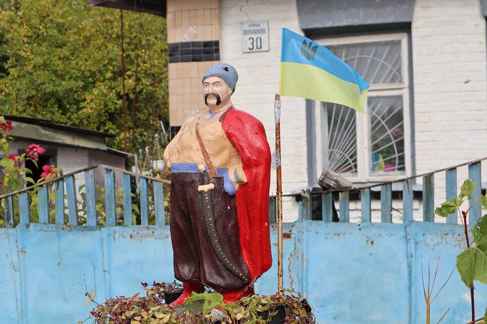 Socha fúzatého kozáka s vlajkou Ukrajiny pred domom