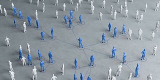 Many miniature people in white and blue are arranged on gray background