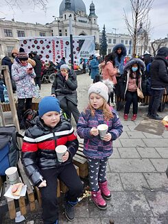 Anna Ševčenko se svojí matkou a dětmi na nádraží ve Lvově během evakuace do Polska. Dobrovolníci pracující na nádraží rodině přinášejí čaj a obložené housky (začátek března 2022).