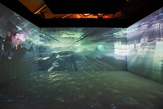 The Evolution of Ent-: QX ist Libby Heaneys aktuelle Ausstellung in der Londoner arebyte Gallery. Für diese Ausstellung hat Libby ein immersives Erlebnis geschaffen und entführt das Publikum auf eine Reise durch drei Erdschichten von Quantenexperimenten mit hybriden Lebensformen und pulsierenden flüssigen Welten. The Evolution of Ent-: QX, 2022, Libby Heaney, Fotos der Installation in der arebyte Gallery. Ent- 2022, im Auftrag von Light Art Space. 