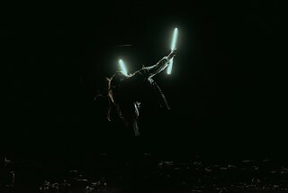 Imagen de una performance con luces en la oscuridad