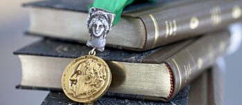 Goethova medaile zavěšená nad knihami.