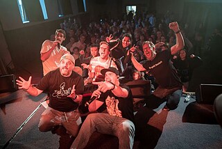 Selfie mit Band auf Bühne und Kindern hinter der Bühne.