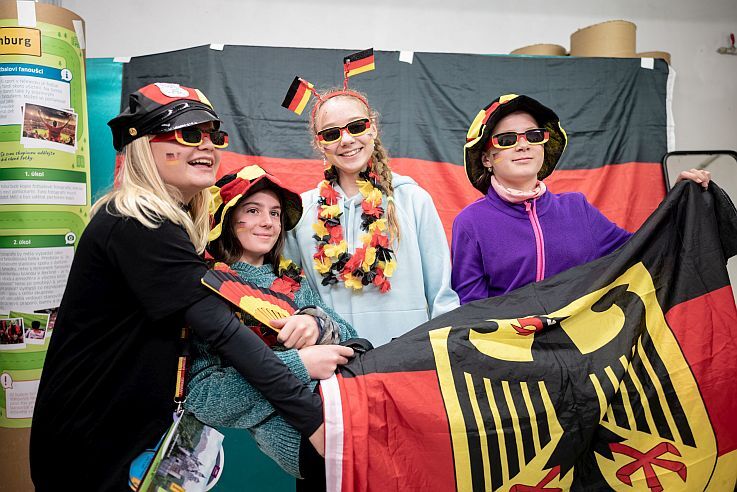 Vier Mädchen posieren von einer Deutschlandflagge, sie lachen.
