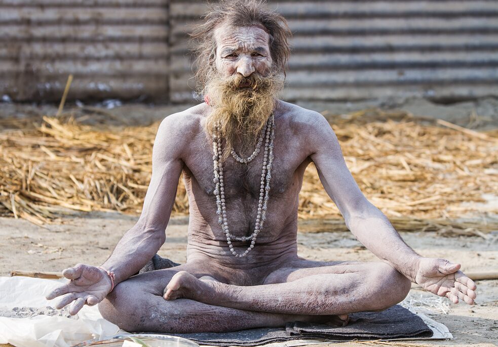 Ein strenggläubiger heiliger Mann sitzt in Meditationshaltung, unbeweglich.