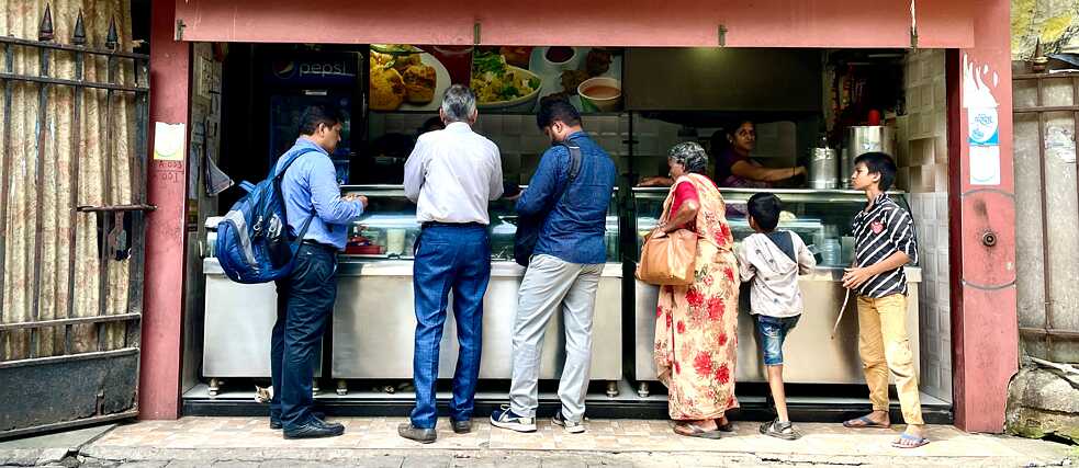 Six people stand in line outside the snack bar waiting for their food