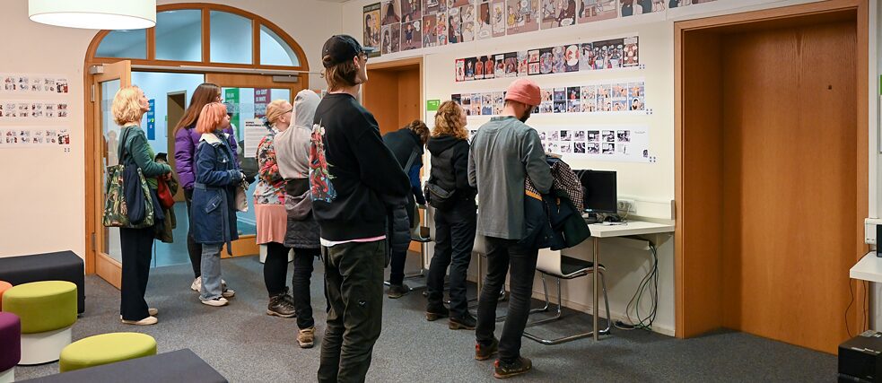 Groß und Klein beim Lesen der Comics/ Besucher*innen lesen die ausgestellten Comics 