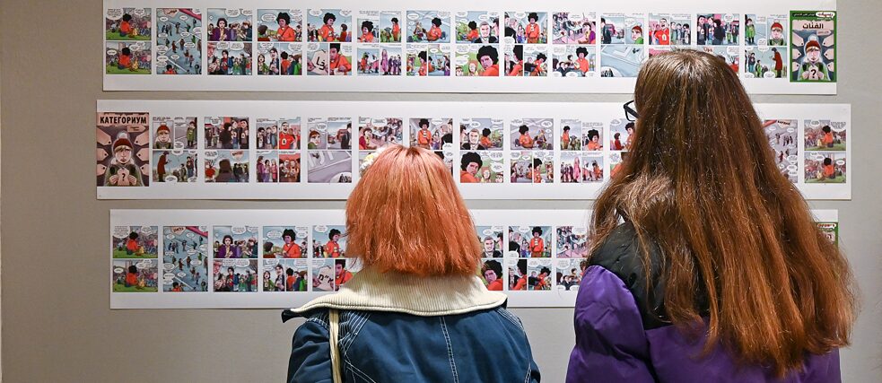 Groß und Klein beim Lesen der Comics/ Besucher*innen lesen die ausgestellten Comics 