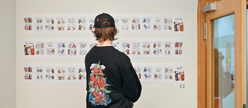 Groß und Klein beim Lesen der Comics/ Besucher*innen lesen die ausgestellten Comics 