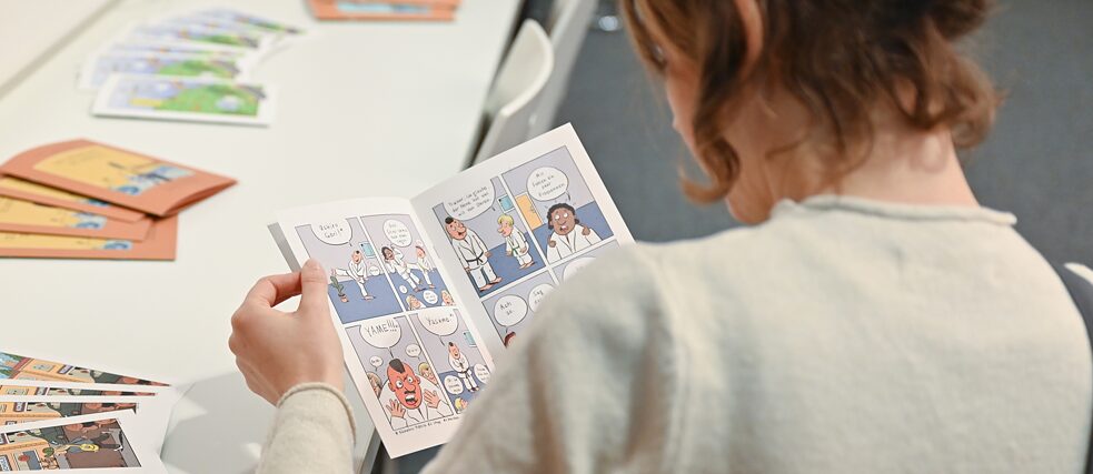 Groß und Klein beim Lesen der Comics/ Besucher*innen lesen die ausgestellten Comics 