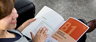 Blick von oben auf eine Schülerin, die ein Goethe-Zertifikat B1 in der Hand hält.