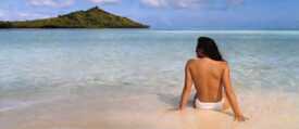 Frau oben ohne an einem Sandstrand 