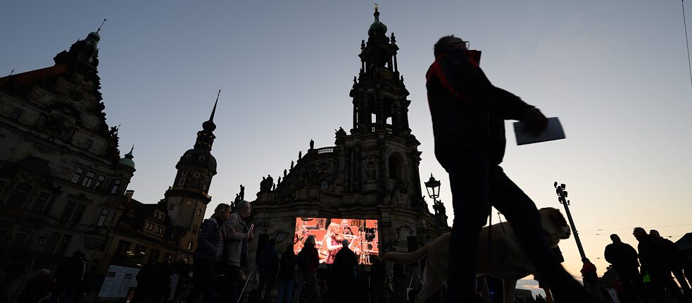 On a screen in front of the Dresdner Hofkirche, passers-by watch the Kyiv Symphony Orchestra’s performance in the Kulturpalast in April 2022. 