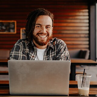 Young man sitting in front of laptop smiling