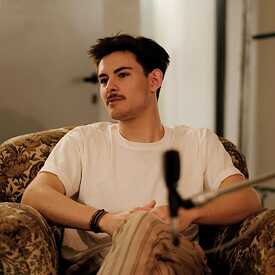 Photo of a young bearded man sitting in an armchair.