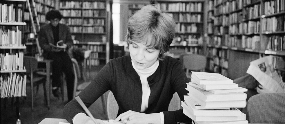 Die Bibliothek im Goethe-Institut London 1980, eine Frau sitzt schreibend an einem Tisch, neben ihr steht ein Bücherstapel.