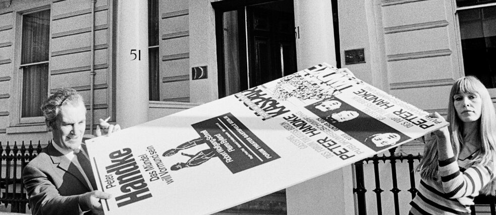 Zwei Mitarbeiter tragen ein Peter Handke Plakat vor dem Eingang des Goethe-Instituts London 1980.