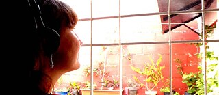 Una mujer con audífonos mira por una ventana