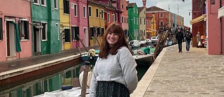 An image of intern Sarah Neil standing at a canal in front of colourful houses 