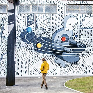 Ein Mann steht vor einer Mauer mit Streetart