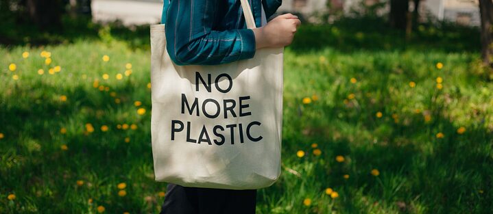 A person carries a cloth bag with the inscription "No More Plastic".