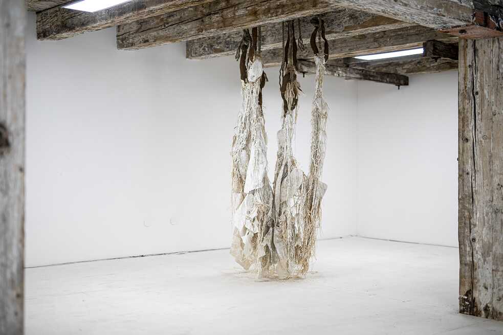 Dominique White, "A Refusal to Be Contained, a Refusal to Die" (2021), Kaolin-Ton, Sisal, Gusseisen, Seile, Kaurimuscheln, zwestörtes Segel, ca. 2.8 x 1.8 x 1m im aqb 2021 