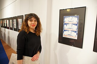 April 2017, Eröffnung der Comicausstellung „New Perspective“ im Goethe-Institut Riga. Im Bild die Künstlerin Natalie Chavarria, im Hintergrund ihr Comic „Empty Houses“.