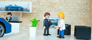 Spielfiguren stellen eine Szene im Autohaus dar