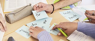 Mehrere Hände sortieren Lernkarten mit deutschen Wörtern
