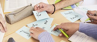 Mehrere Hände sortieren Lernkarten mit deutschen Wörtern