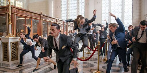 People in business attire euphorically doing acrobatics inside a bank reception area