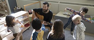 Um professor toca violão para seus alunos