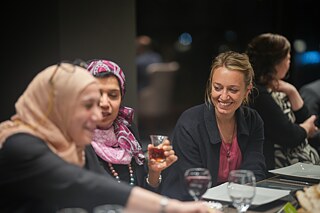 Drei Frauen sitzen gemeinsam am Tisch und lachen