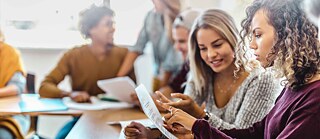 jovem aluna sentada em mesa le texto em folha de papel