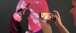 Eine Frau nimmt eine tanzende Person mit dem Handy auf