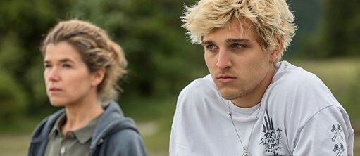 Ein junger Mann schaut mit ernstem Blick in die Ferne. Neben ihm steht eine Frau, die in die gleiche Richtung schaut. hacia la lejanía en un entorno verde.