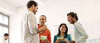 Vier stehende Personen machen lachend eine Übung