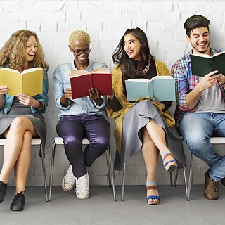 Vários jovens estudantes sentam-se ao lado uns dos outros em cadeiras e lêem em livros. As fotos da série "YOUNG LEARNERS" mostram grupos de jovens aprendizes - crianças e adolescentes - que devem transmitir diversão na educação, na aprendizagem e na língua alemã.