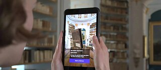 Im prunkvollen Rokokosaal der Herzogin-Anna-Amalia-Bibliothek einfach mal virtuell ein Buch aus dem Regal nehmen? Die Augmented-Reality-App „Aufgeschlagen!“ der Klassik Stiftung Weimar macht’s möglich. 