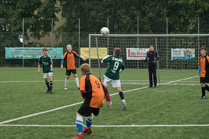 Dva týmy hrají fotbal. Kluk běží k míči.