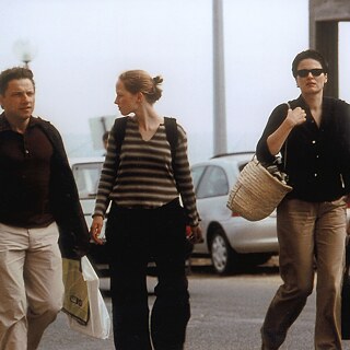 Σκηνή από την ταινία «The State I Am In»: Ένας άντρας και μια γυναίκα με την έφηβη κόρη τους περπατούν στο δρόμο. Οι γονείς κρατούν τσάντες και η κόρη τους ένα σακίδιο.