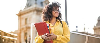 Eine junge Frau mit Büchern auf dem Arm