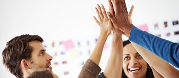 Eine Gruppe Deutschlernende klatscht die Hände zusammen nach einem erfolgreichen Workshop