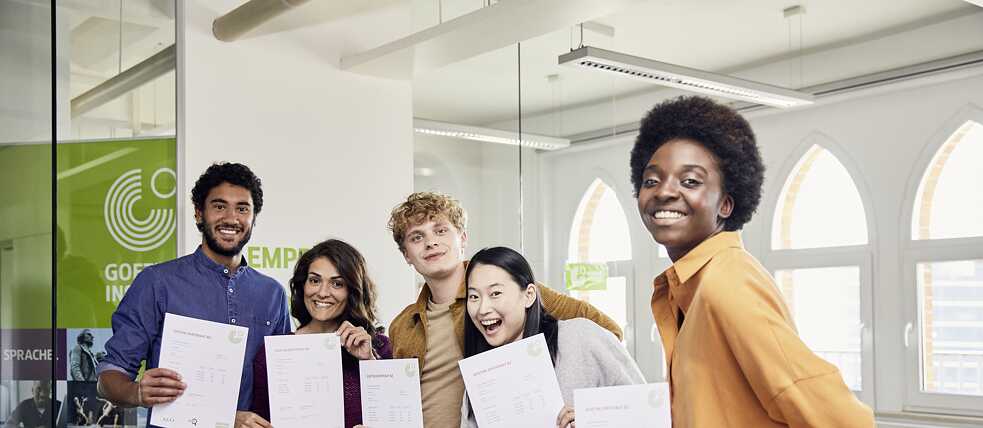 The exam participants have passed the exam. They are happy and proud to show off their Goethe certificates.
